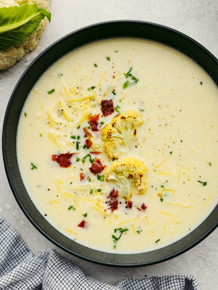 A bowl of cauliflower soup garnished with chives and bacon. 