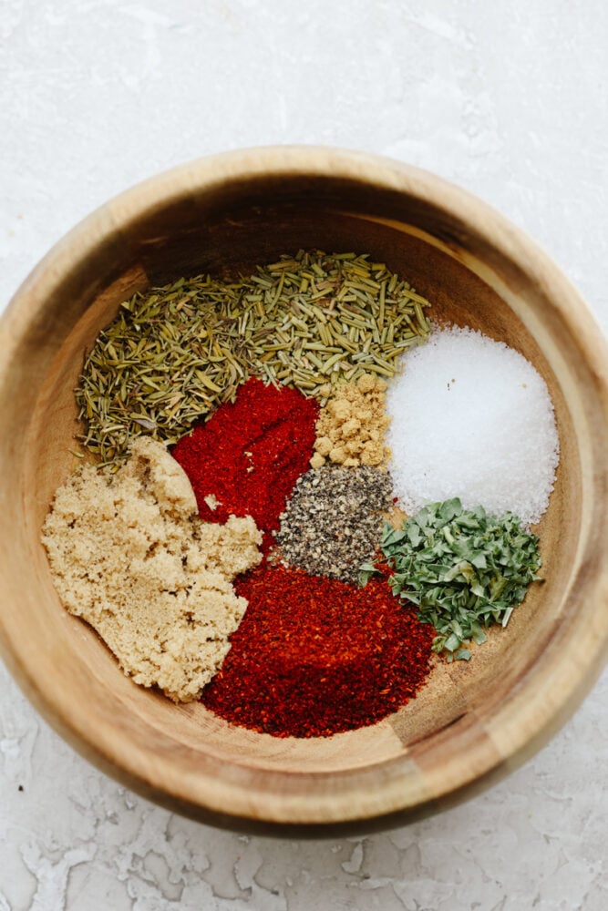 A wooded bowl filled with seasonings ready to be mixed together. 