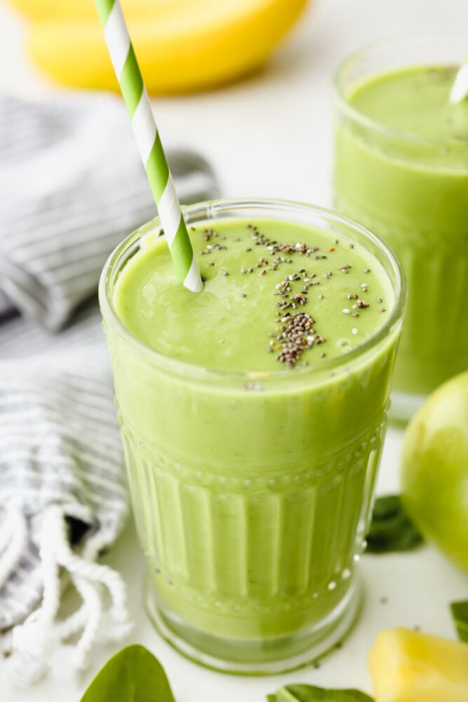 A green detox smoothie with a straw and chia seeds on top! 