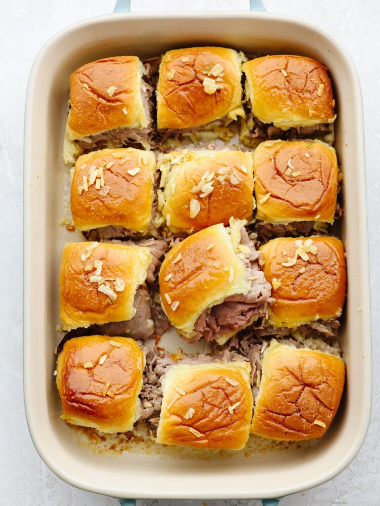 A pan filled with 12 baked sliders.
