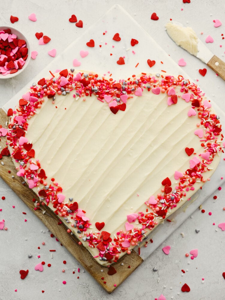 A whole heart-shaped cake, topped with festive sprinkles.