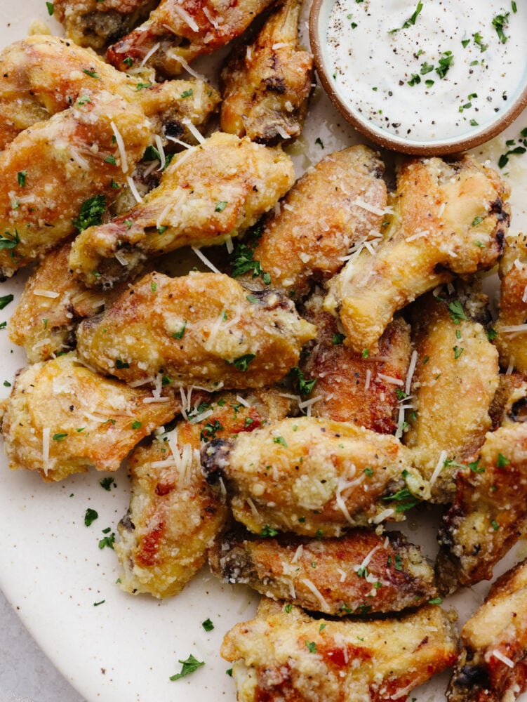 If you love wings, then these parmesan garlic ones are going to blow you away! The parmesan, honey, and garlic sauce are so delicious that these wings are going to fly off of your table! A platter of parmesan garlic wings.