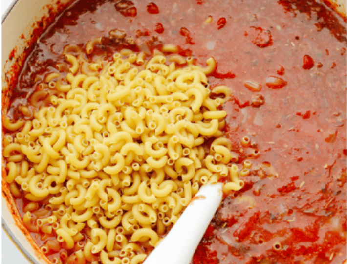 American Goulash is my kind of comfort food! It's rich, savory, and full of that cozy, tomato-y goodness. It’s hearty, easy to make, and one bite will have you hooked just like my family is! Macaroni noodles and beef added into the pot ready to simmer together.
