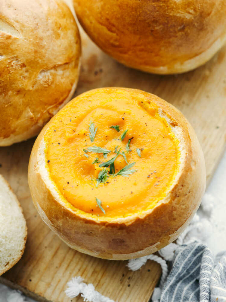 A bread bowl filled with carrot soup. 