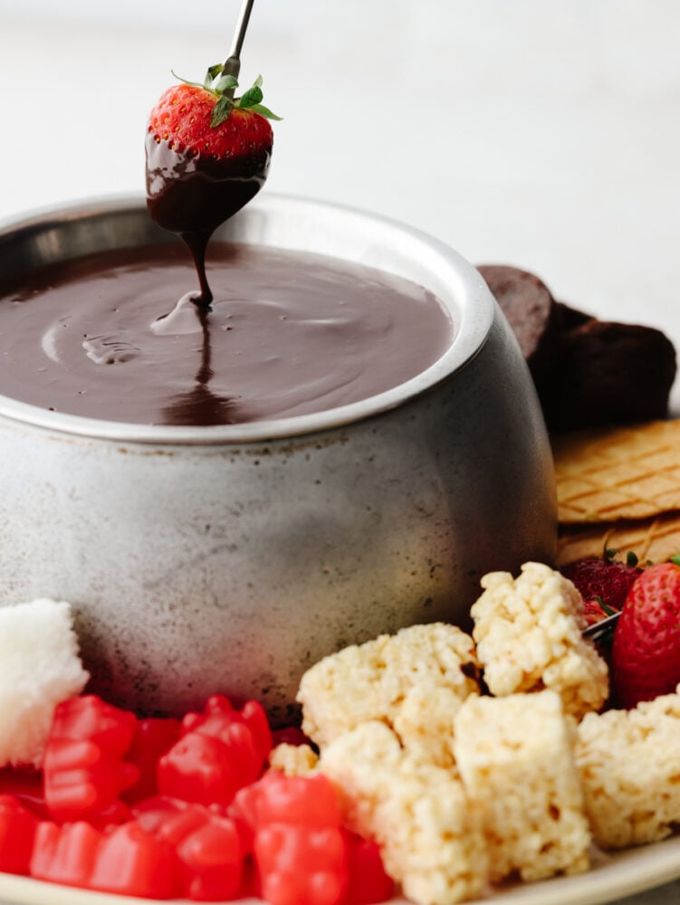 A strawberry being dipped into chocolate fondue.