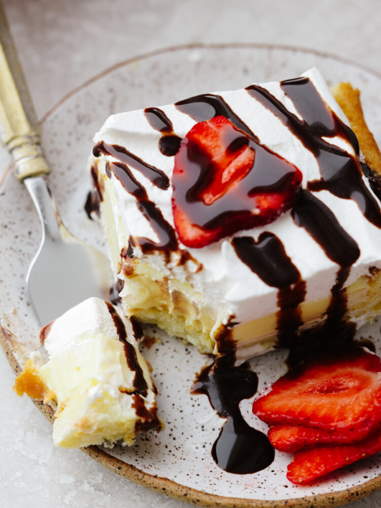Taking a bite of eclair cake topped with strawberries and chocolate sauce.