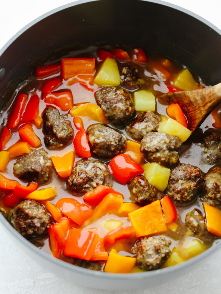 A pot filled with sauce, meatballs and vegetables. 