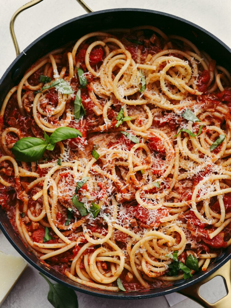 A pan of bucatini all'amatriciana garnished with basil. 