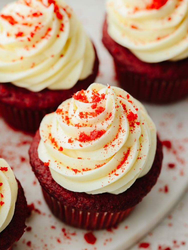 The top view of a red velvet cupcake with red velvet crumbs sprinkled on top. 