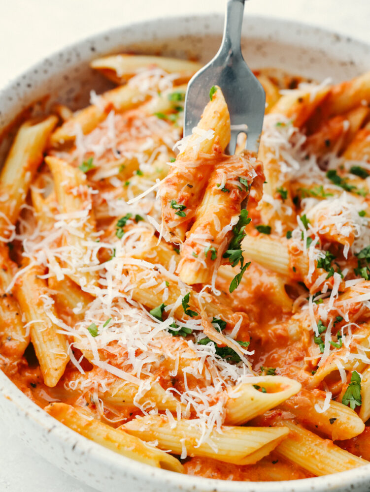 Closeup of roasted red pepper pasta garnished with herbs and cheese.