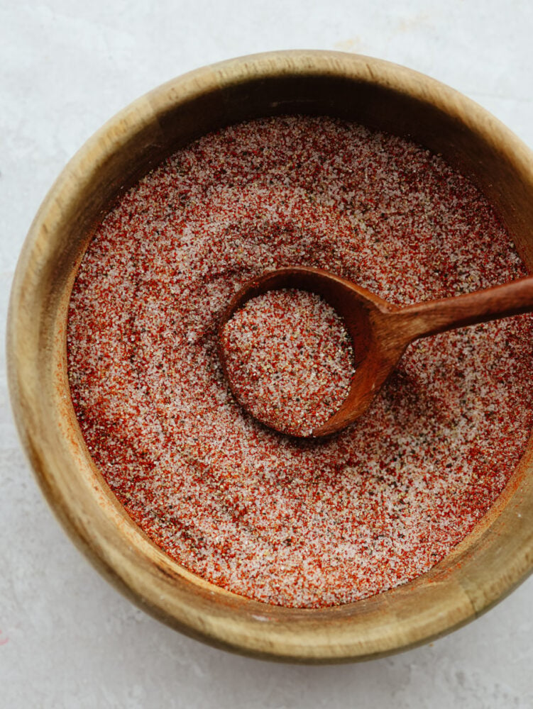 Seasoning salt in a wooden bowl being dished with a wooden spoon. 