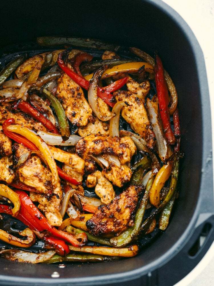 Chicken fajitas cooked in an air fryer basket. 