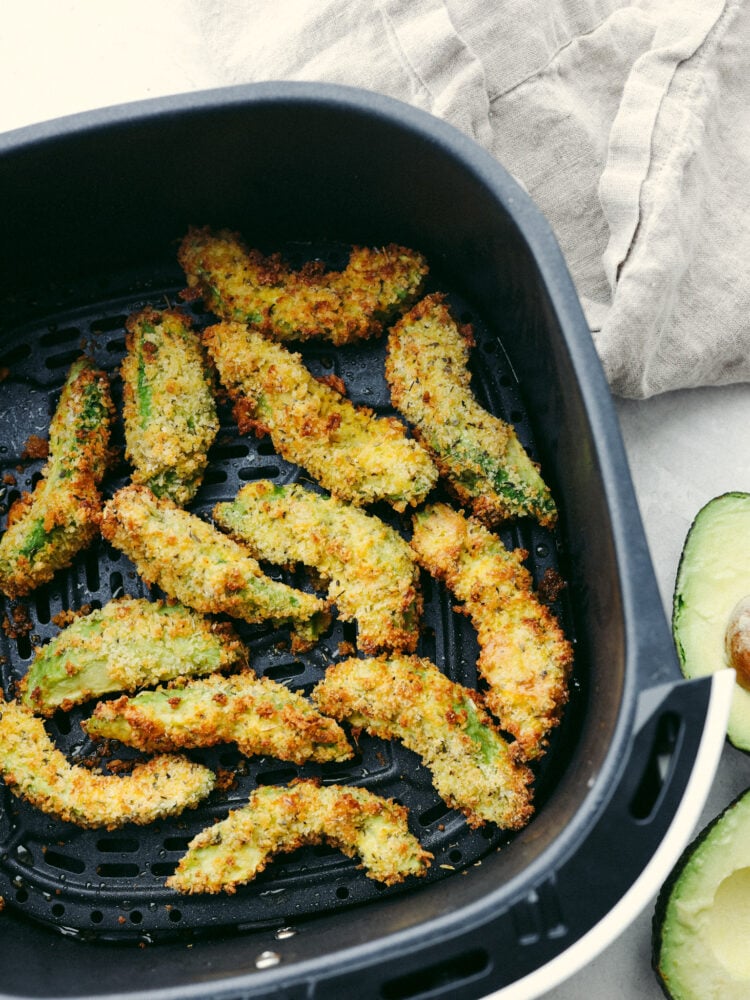 Avocado fries in the basket of an air fryer.