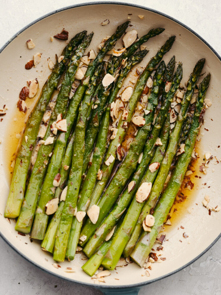 Roasted asparagus with almonds in a white and blue bowl.