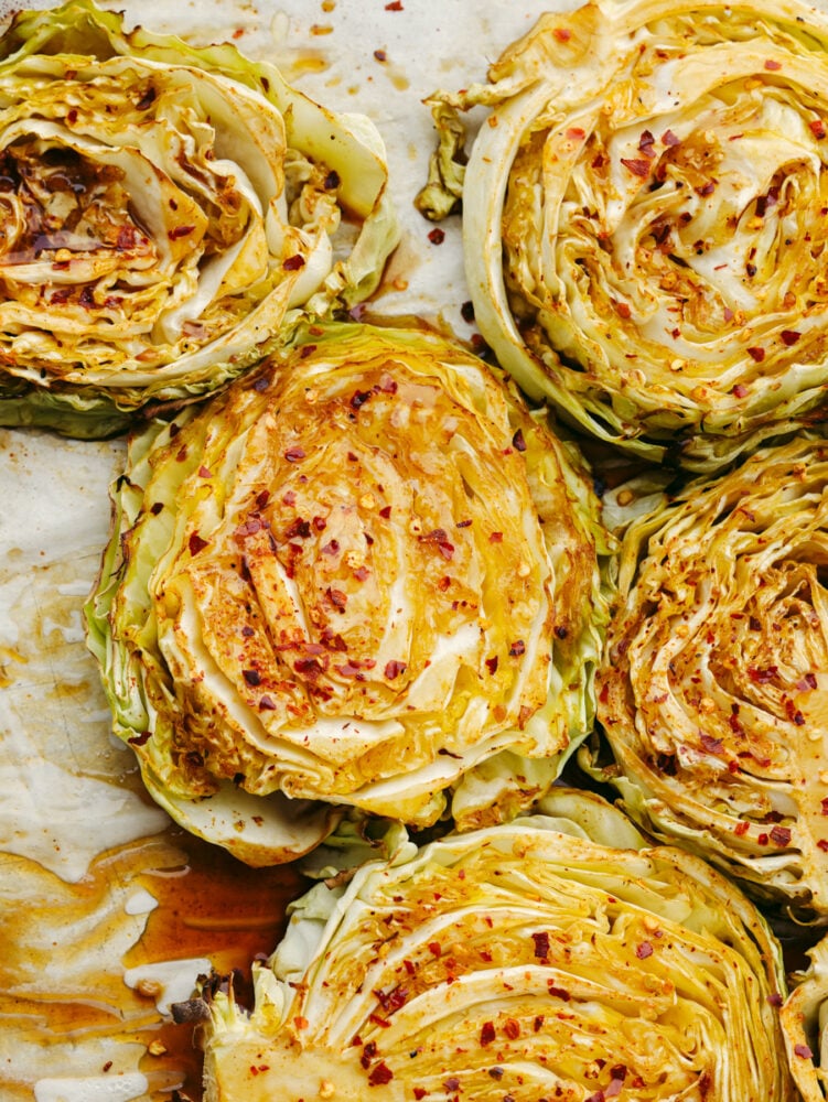 Top-down view of cabbage steaks topped with soy sauce and seasonings.
