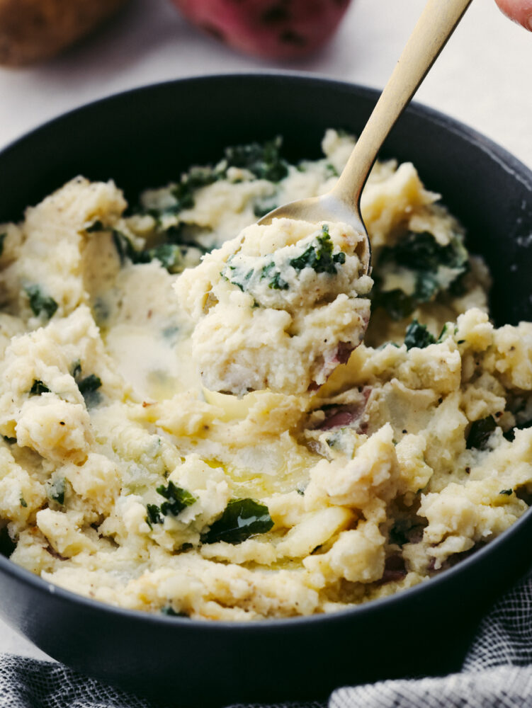 A close up of a spoon scooping colcannon out of a bowl. 