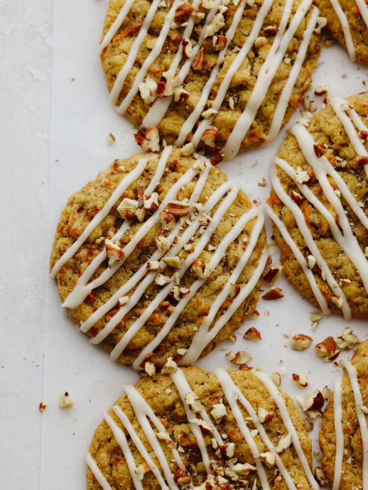 Top-down view of baked carrot cake cookies on parchment paper.