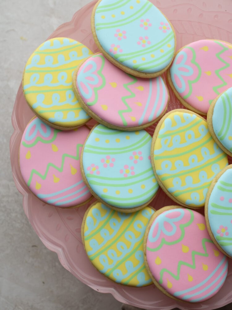 Easter egg cookies stacked on a pink plate.