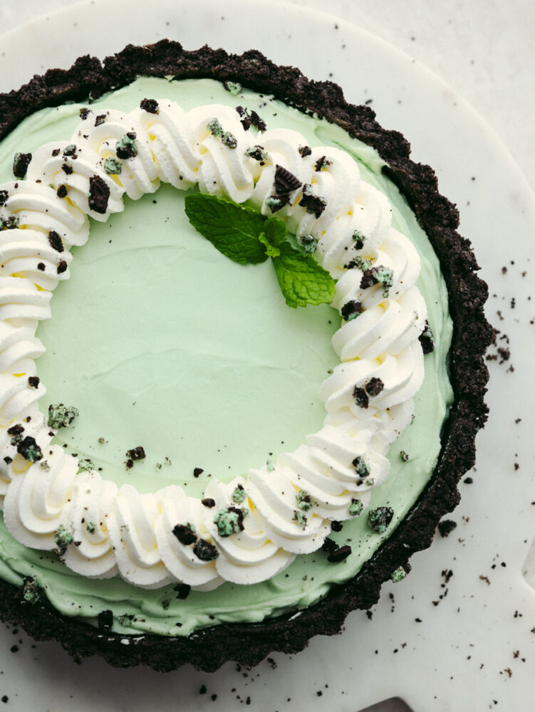 The top view of the pie that is garnished with cream swirls and crushed andes mints and oreo cookies. 