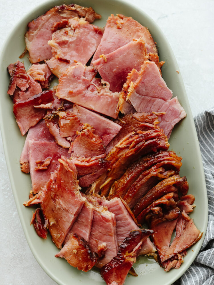 A ham on a green platter sliced, cut and ready to eat.