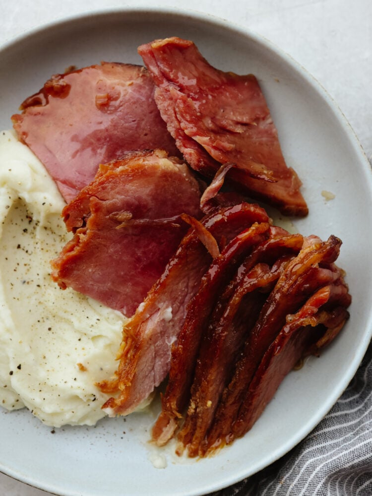 Instant pot ham on a plate with some mashed potatoes. 
