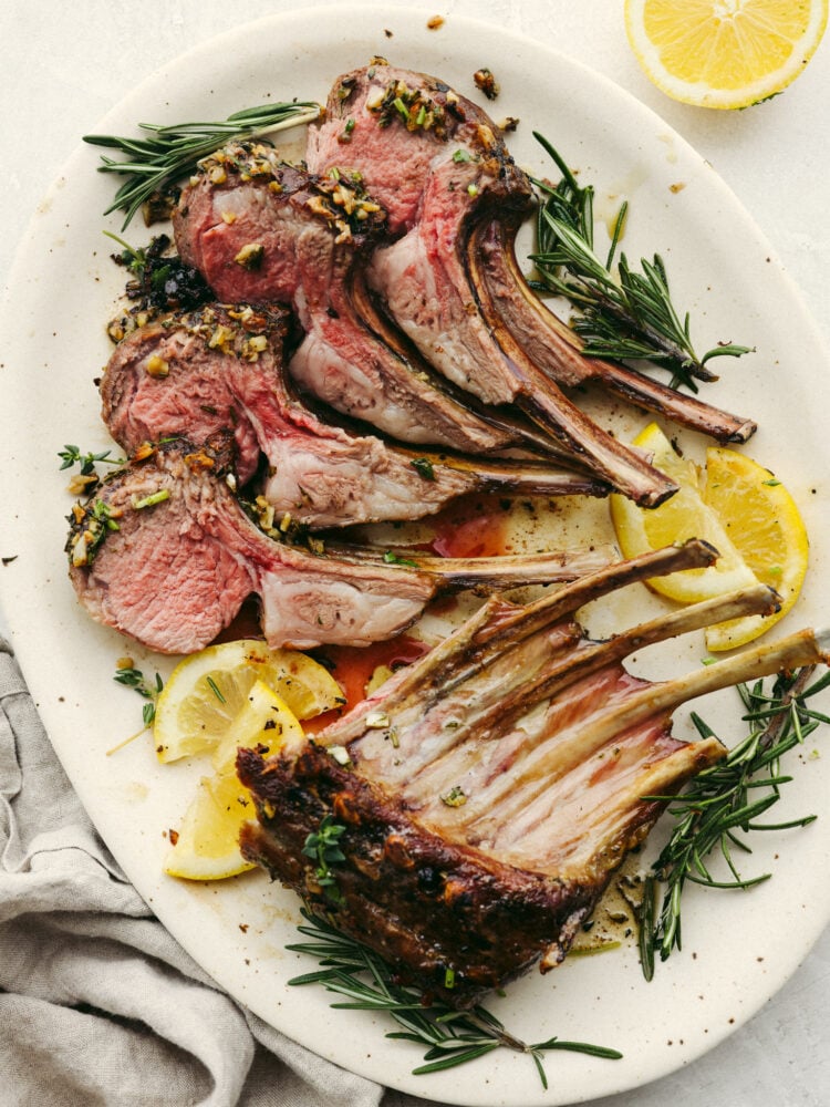 A rack of lamb cut and plated with some lemons and herbs. 