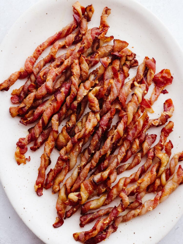 Top-down view of twisted bacon on a white plate.