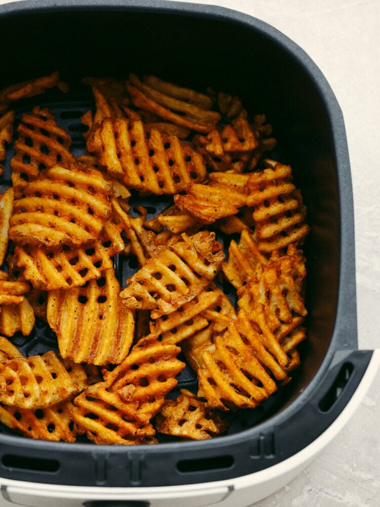 Waffle fries in an air fryer basket. 