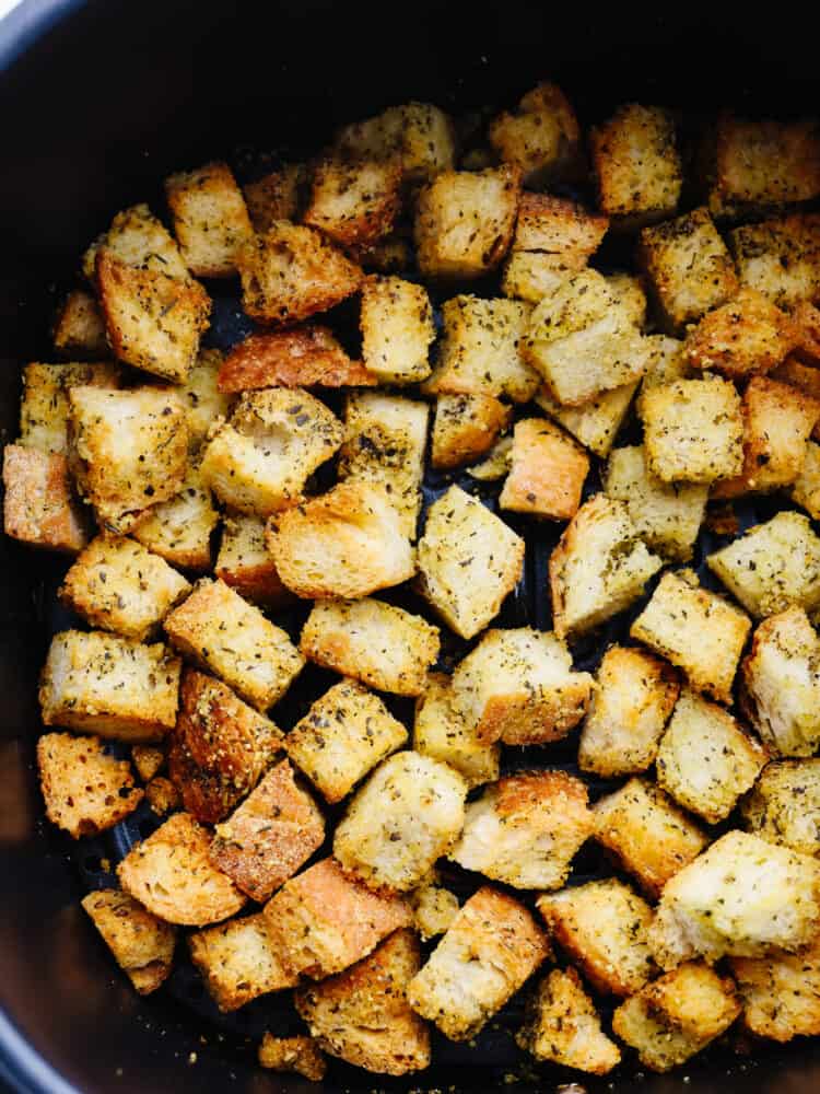 Closeup of croutons in air fryer basket.