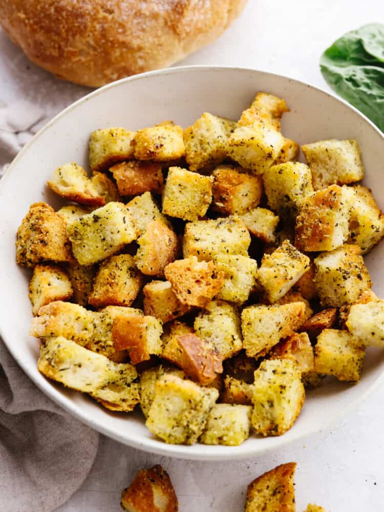 Seasoned croutons in a white bowl.