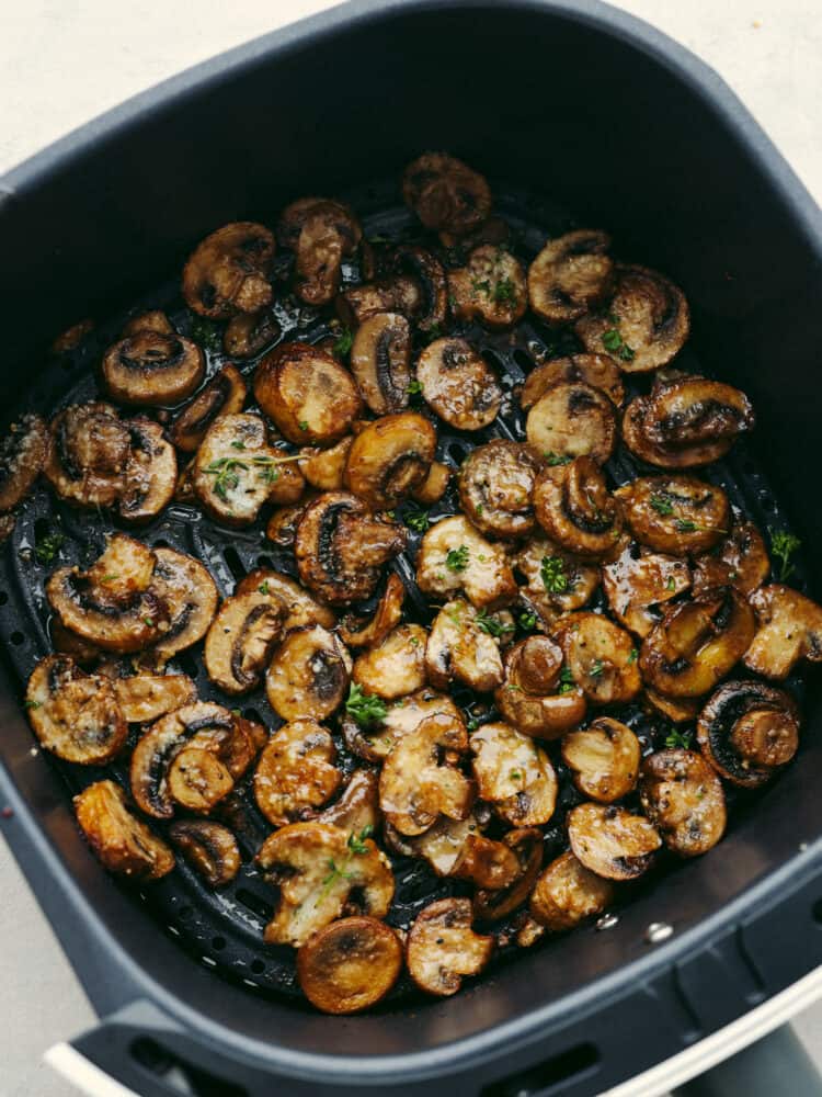 Cooked mushrooms in the bottom of an air fryer basket.