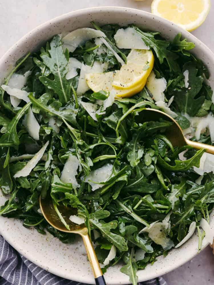 Top-down view of arugula salad, garnished with lemon and ready to serve.
