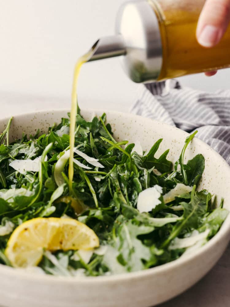 Closeup of lemon vinaigrette being drizzled over salad.