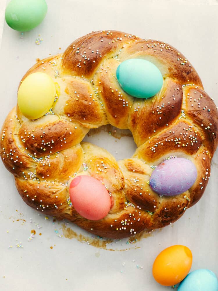 Top-down view of an Easter bread wreath, decorated with sprinkles and Easter eggs.