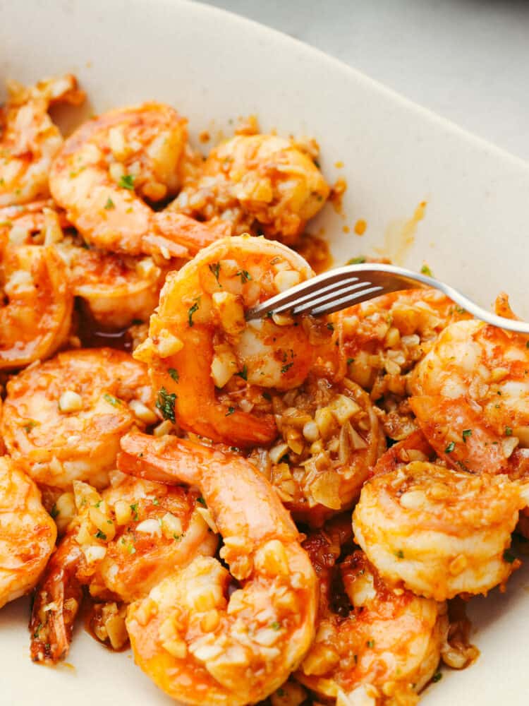 A piece of shrimp being skewered with a fork.