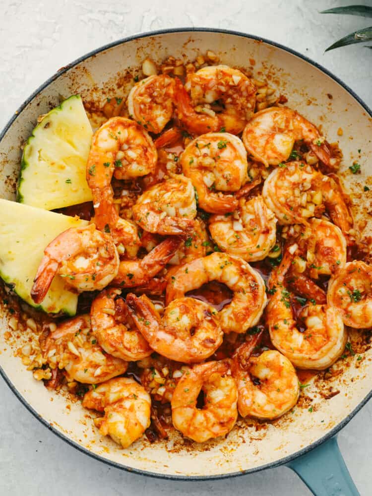 Top-down view of garlic shrimp in a white and blue skillet.