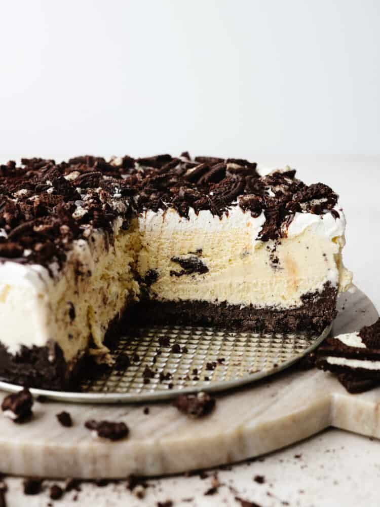 The side view of a cookies and cream ice cream cake with a slice taken out so that you can see the inside. 
