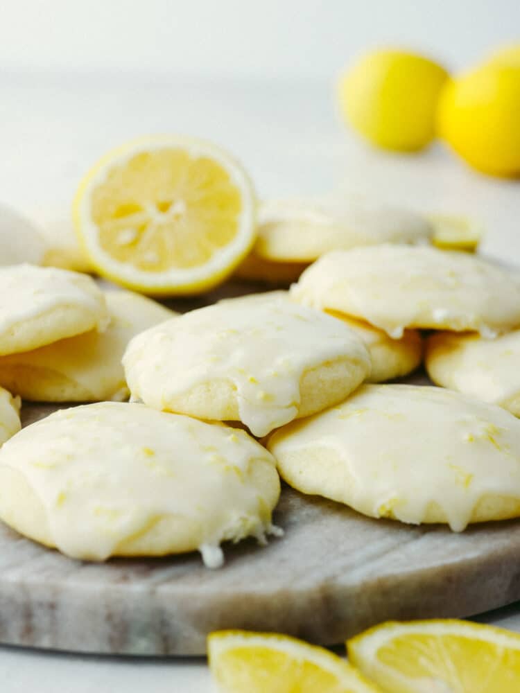 Lemon ricotta cookies on a cutting board with lemon slices scattered around. 