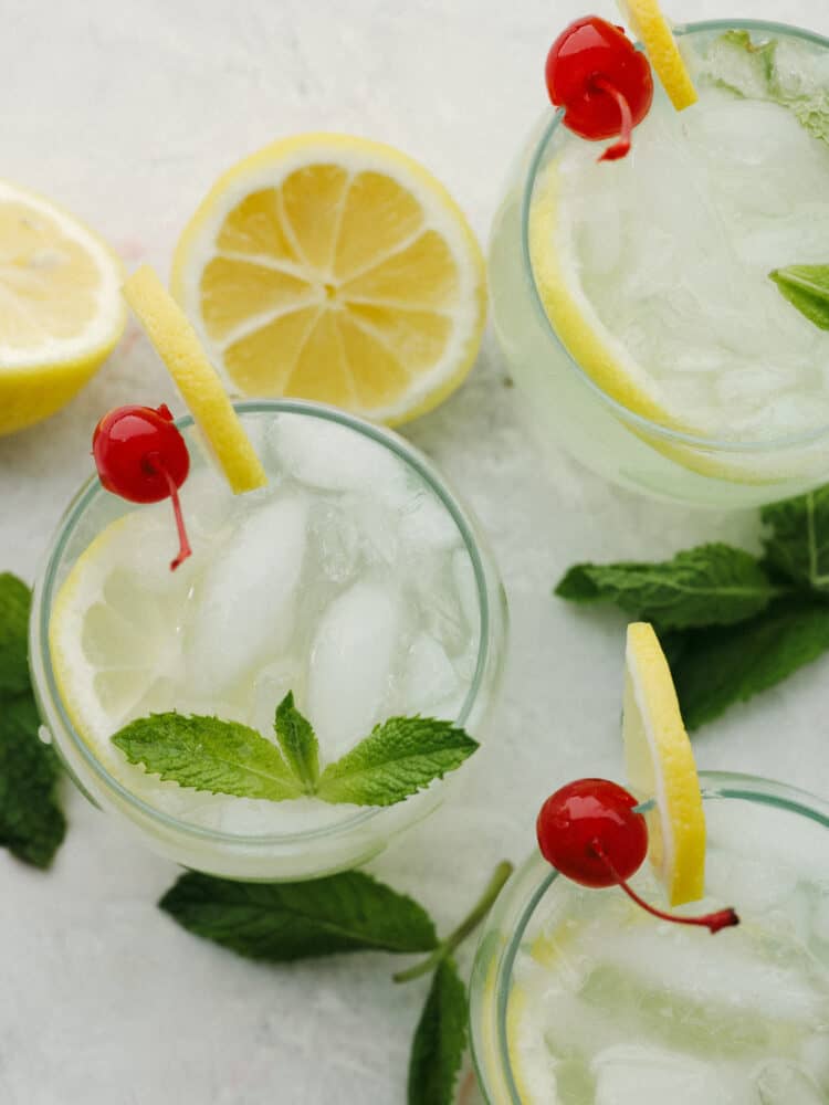 The top view of glass cups filled with mint julep and garnished with cherries, lemons and mint sprigs. 