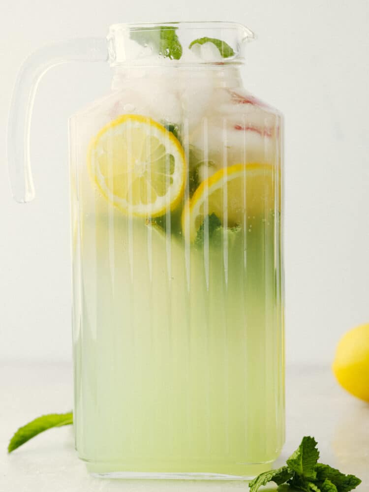 A ribbed, clear pitcher filled with mint julep. 