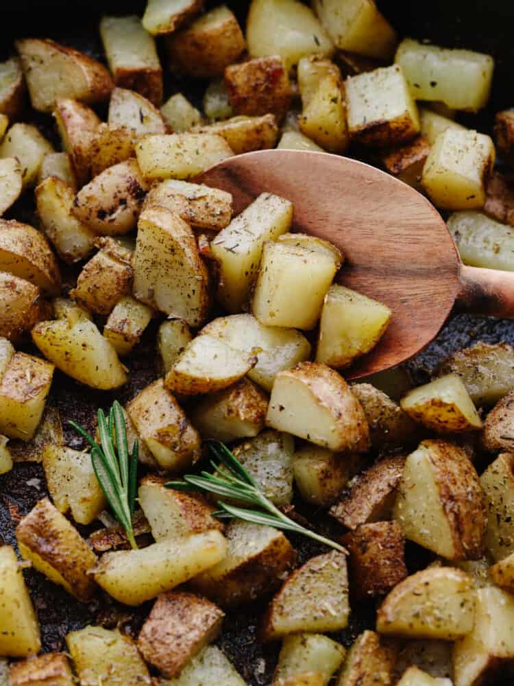 Potato chunks being scooped up with a wooden spoon.