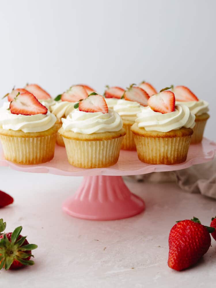 Strawberry shortcake cupcakes on a pink cake platter. 