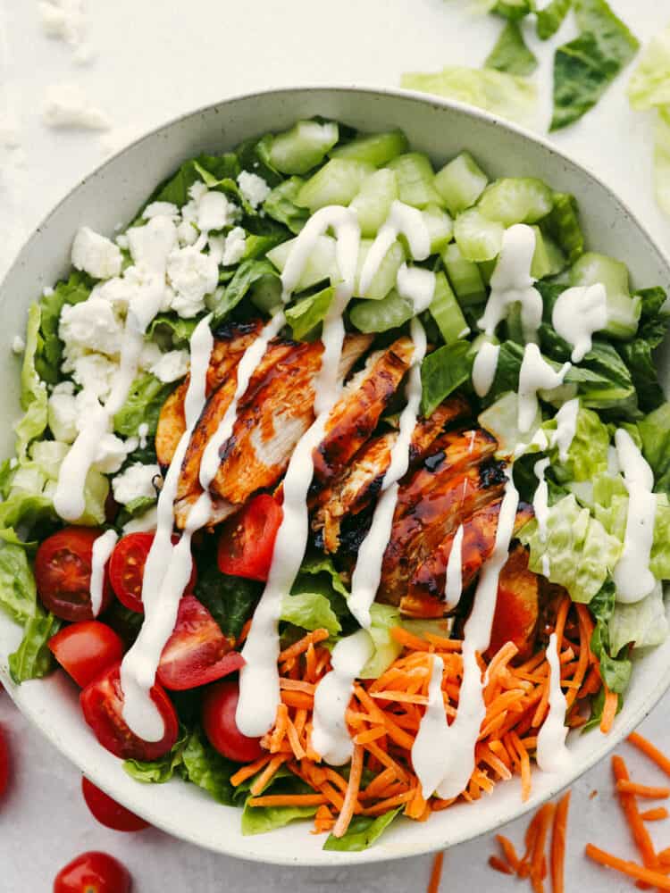 The top view of buffalo chicken salad in a bowl. Ranch dressing is drizzled on top. 