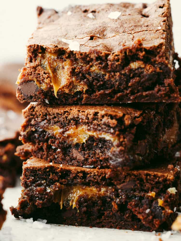 A zoomed in shot of salted caramel brownies with a bite taken out of the top one. 