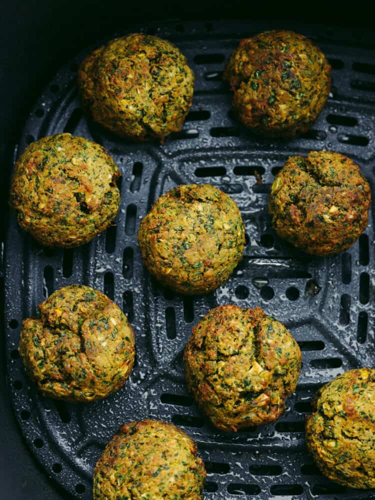 Overhead view of cooked crispy falafel balls in the basket of the air fryer.