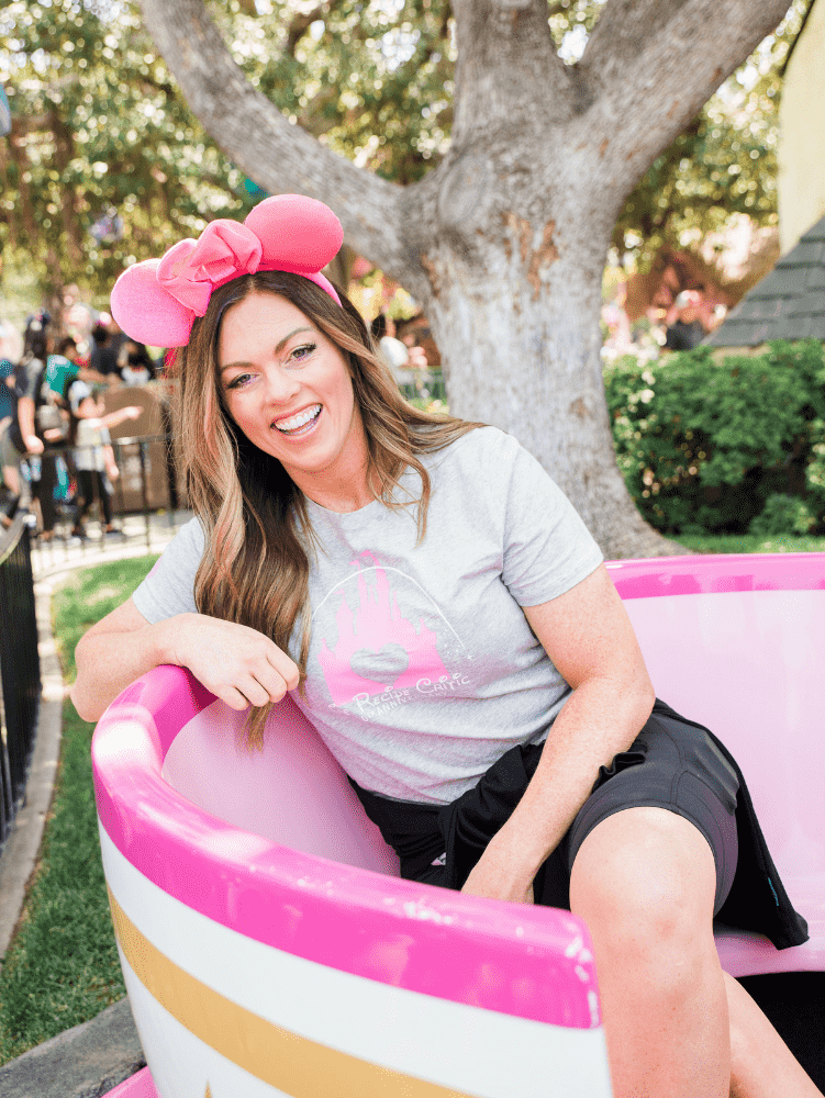A woman sitting in a pink Disneyland teacup.