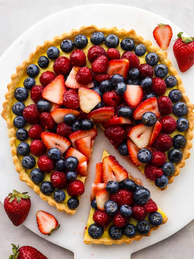 Top-down view of a berry tart with a slice taken out of it.