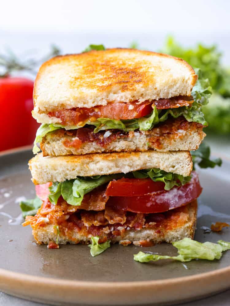 A BLT sandwich cut in half and stacked on top of each other.