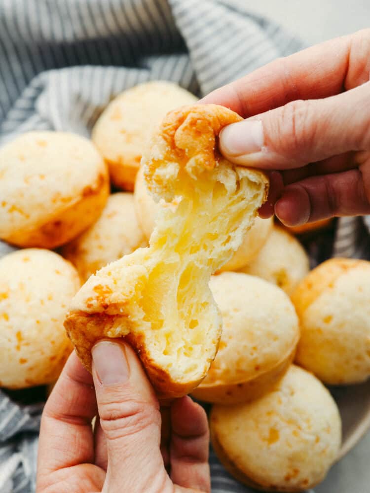 A close up of a Brailian cheese bread being broken in half. 