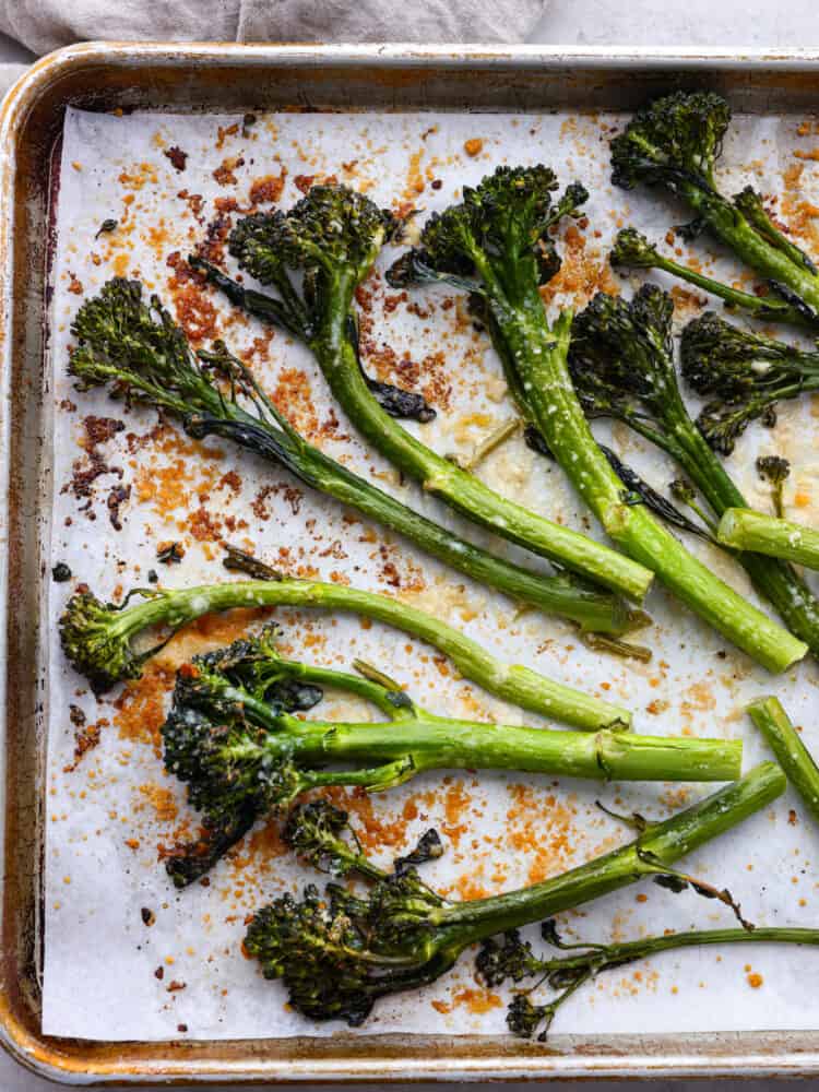 Roasted broccolini on a baking sheet with parchment paper. 